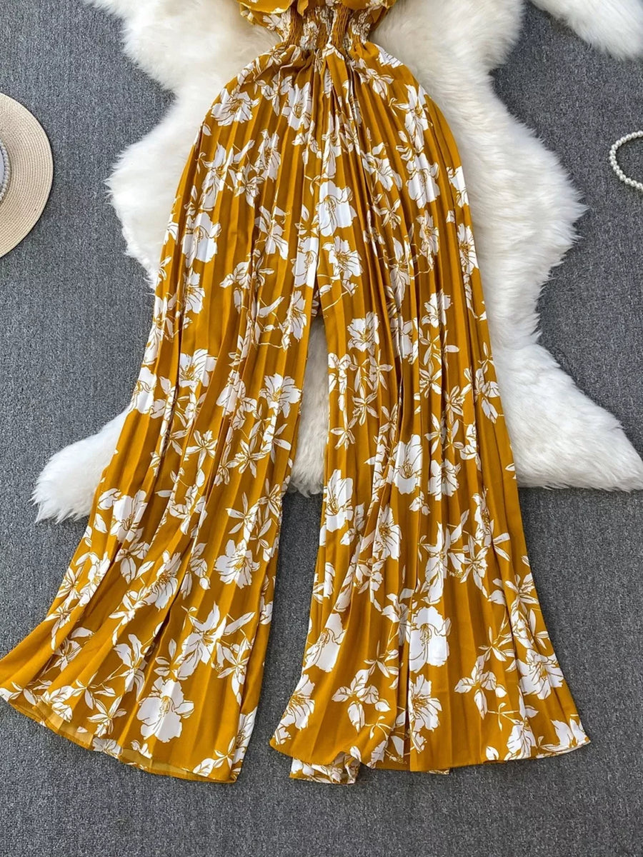 Yellow floral pleated wide-leg romper with smocked waist and flowy legs.