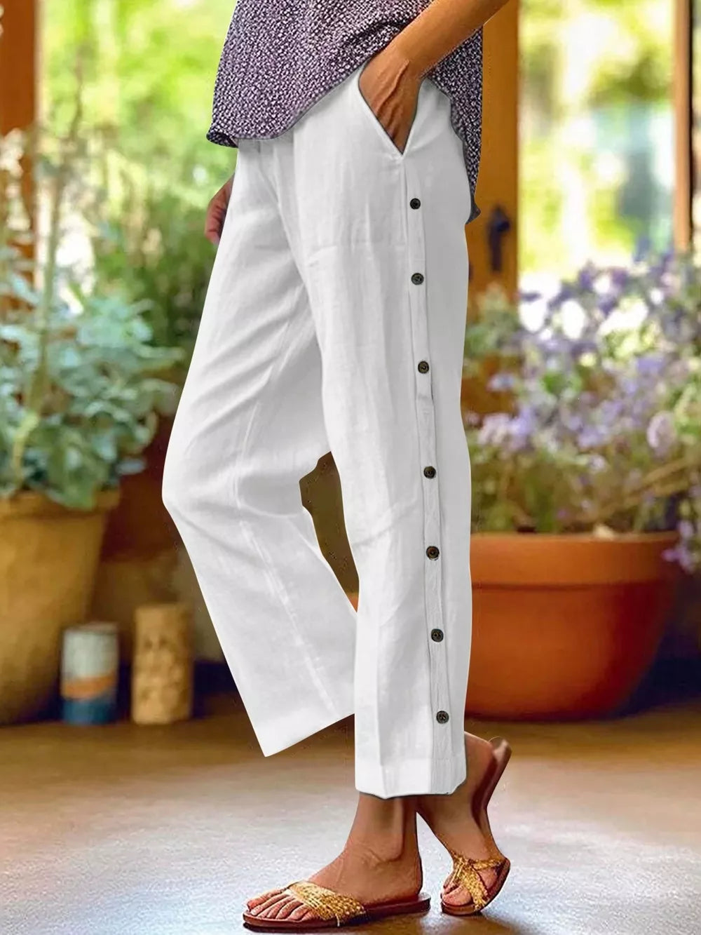 White relaxed fit pants with decorative side buttons and pockets.