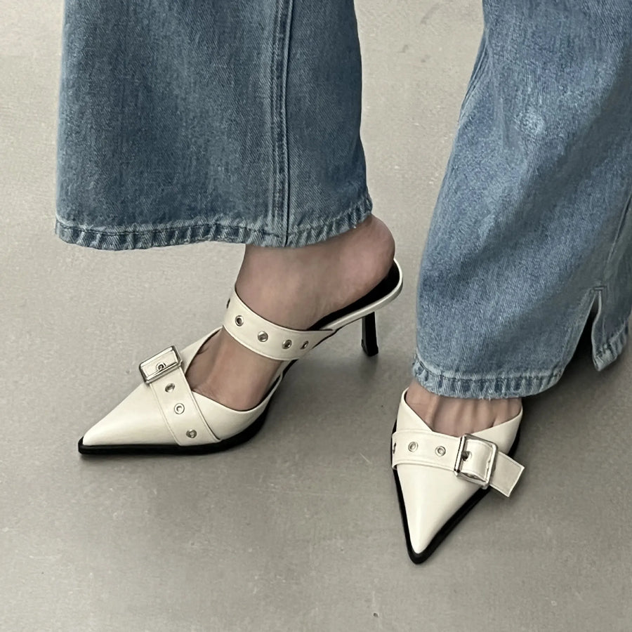 White pointed buckle mule heels with silver hardware and ankle strap detail.