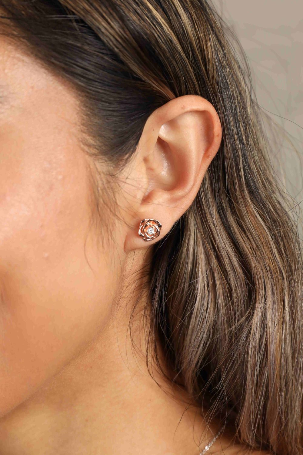 Rose gold rose stud earrings with diamond center detail.