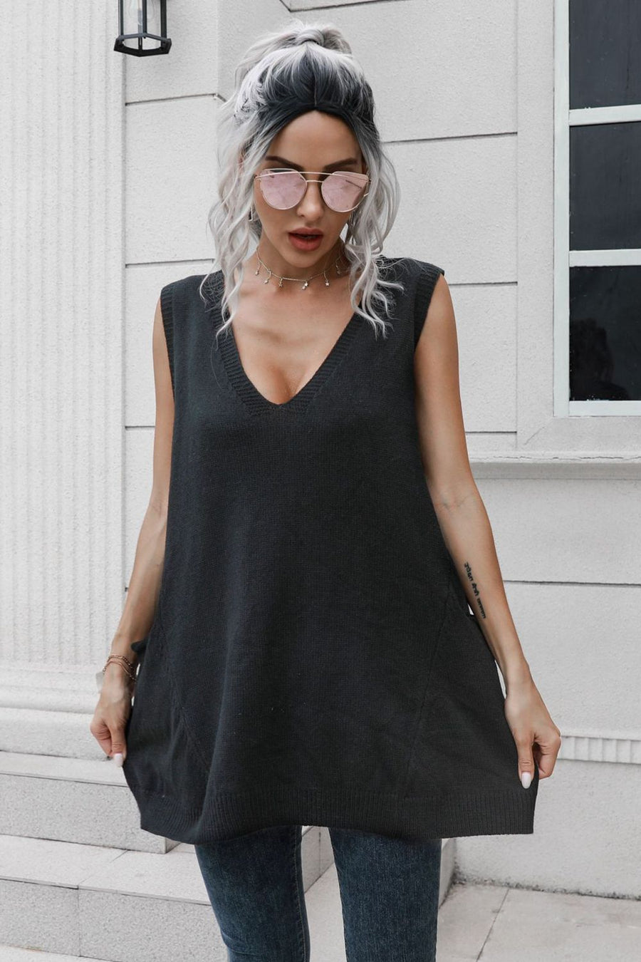Black oversized knit vest with V-neck and pockets, styled with jeans.