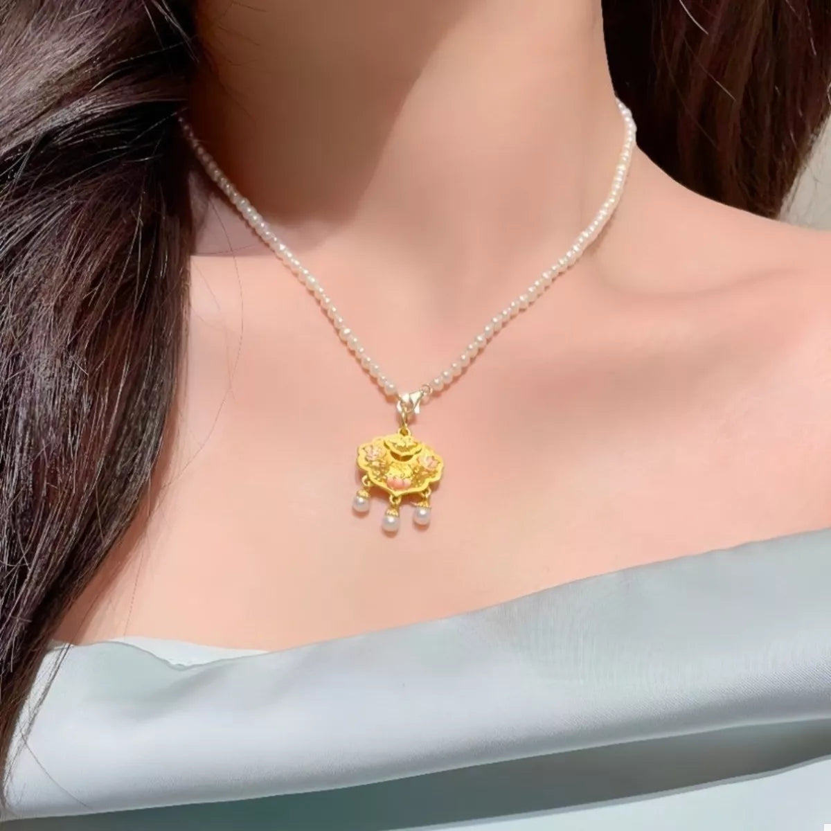 Gold lotus pendant necklace with pearl accents on a pearl strand.