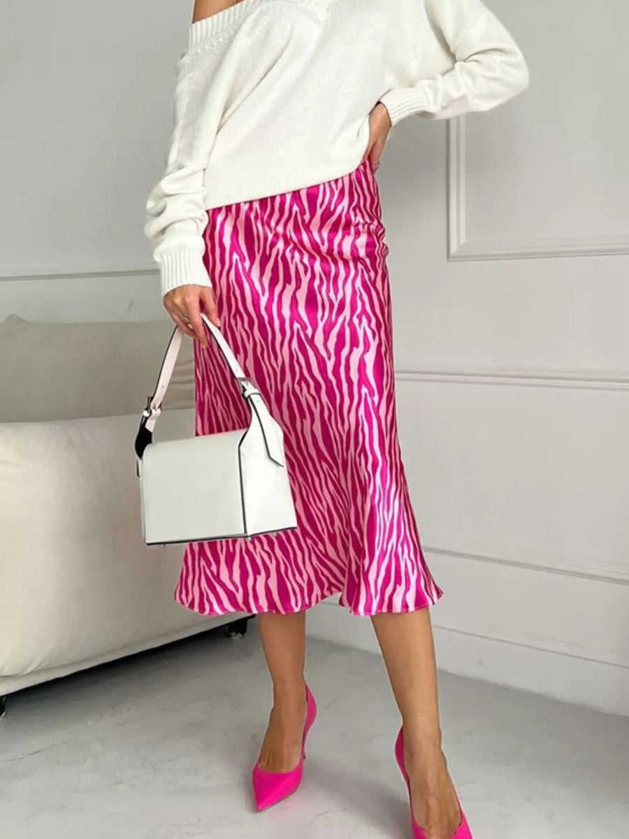 Satin midi skirt with pink zebra print, draped waist, and a white off-the-shoulder sweater.
