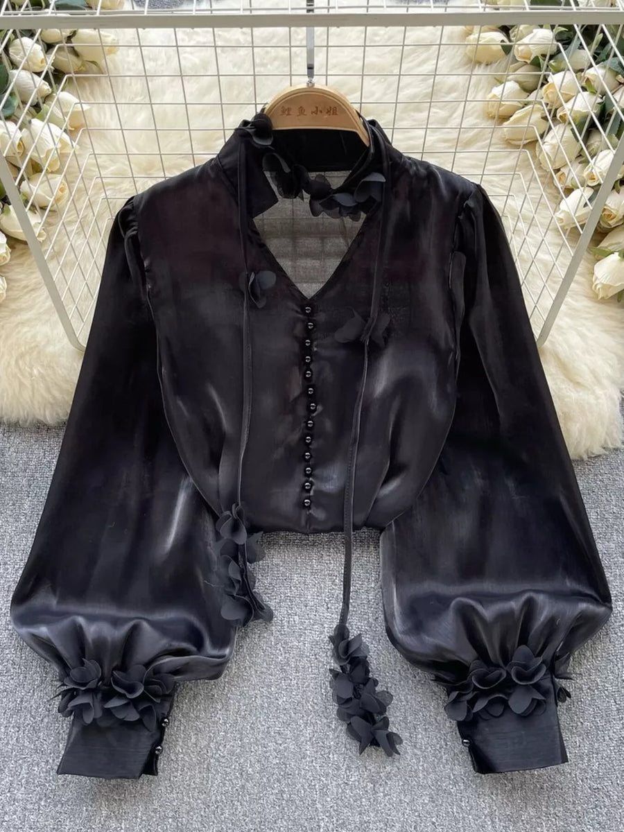 Black button-down shirt with floral appliqué details and balloon sleeves.