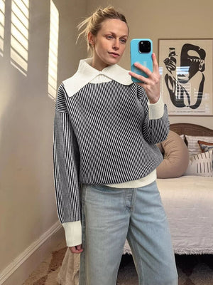Black striped knit sweater with white contrast collar and cuffs.