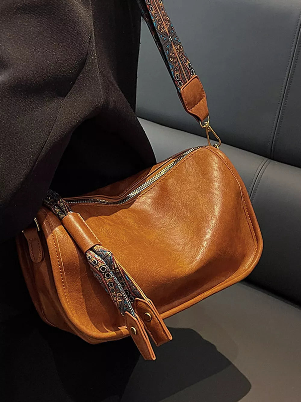 Brown crossbody bag with textured strap and tassel detail