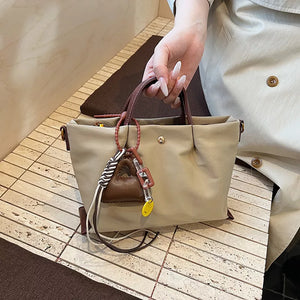 Compact Khaki nylon handbag with brown handles and playful charms.