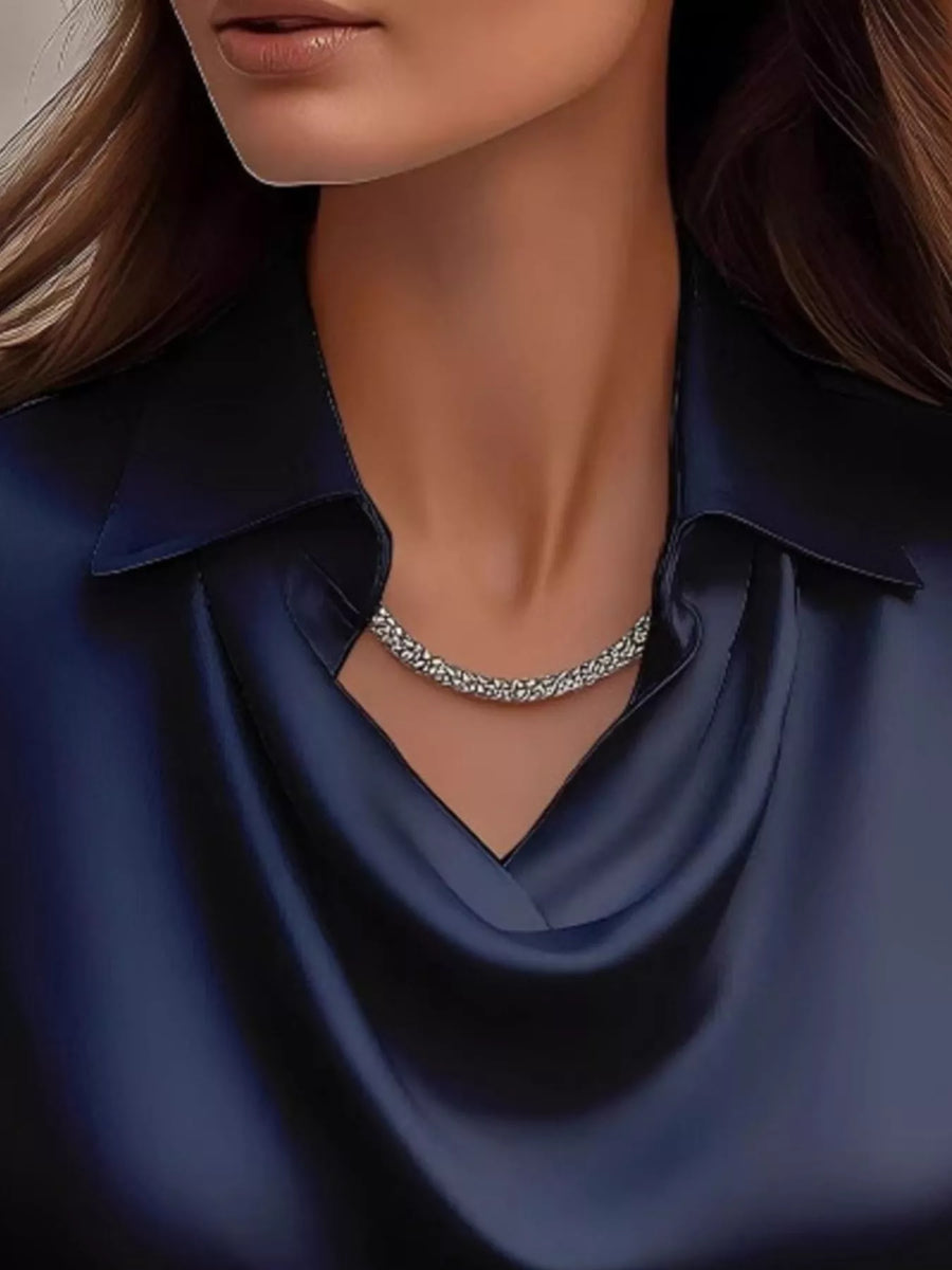 Dark blue satin cowl neck blouse with a silver necklace.