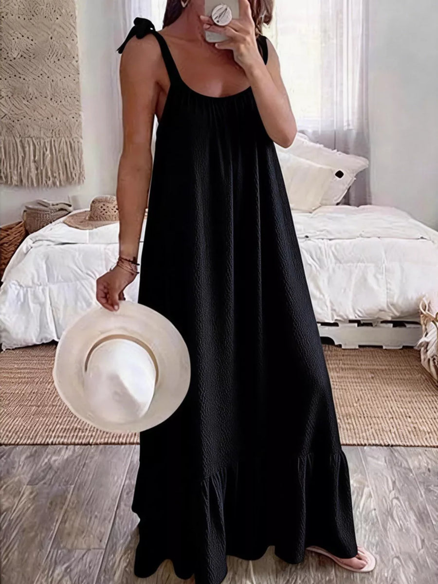 Black tie strap maxi dress with textured fabric and ruffled hem.