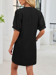 Black cotton dress with short puff sleeves and a textured finish.