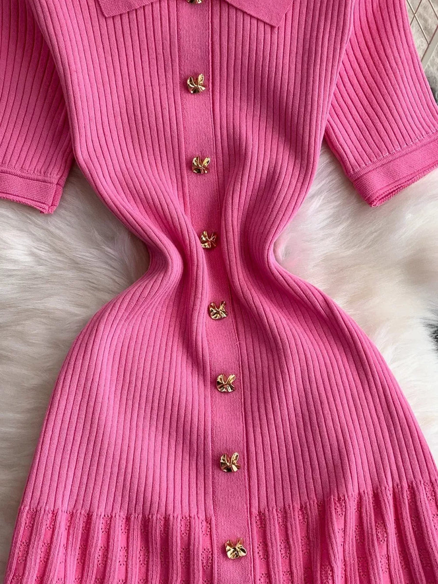 Pink ribbed knit midi dress with gold butterfly button detail and collared neckline.