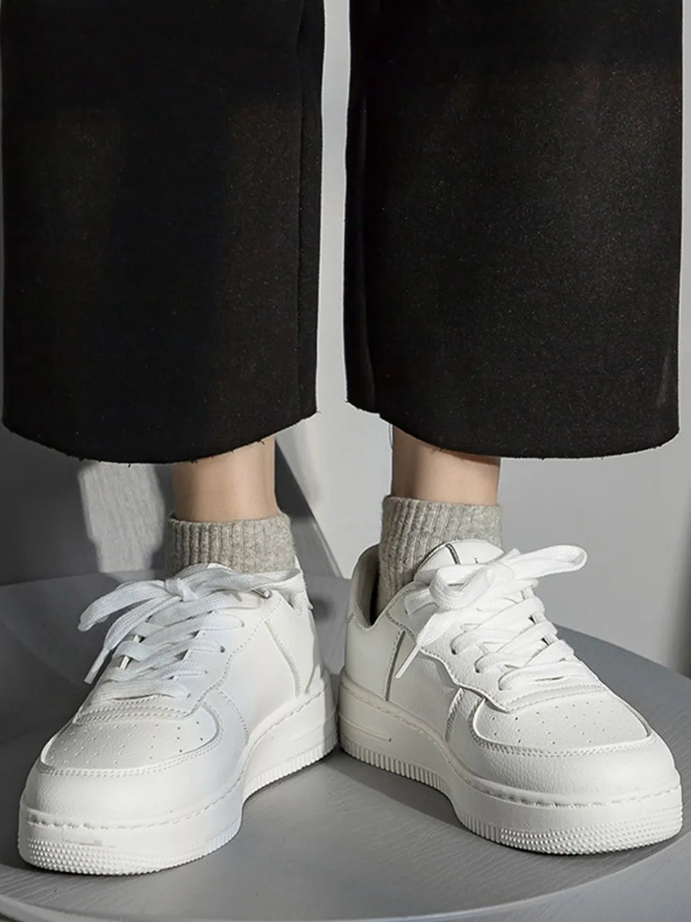 White minimalist platform sneakers with white laces and a thick sole.