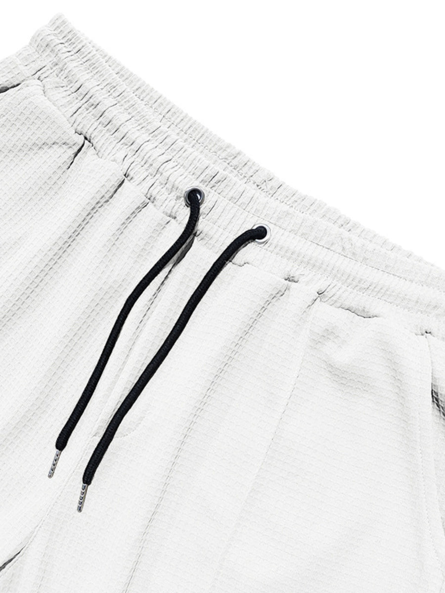 White textured drawstring sweatpants with black drawstrings and metal tips.