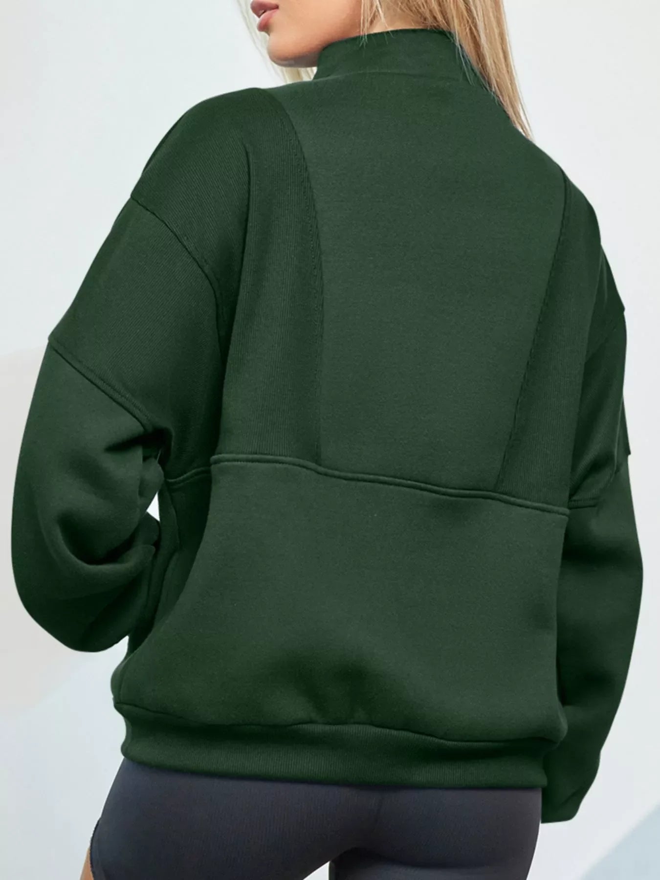 Dark green half zip stand collar sweatshirt with ribbed panel details on the back and sleeves.