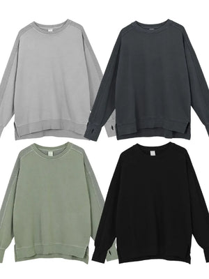 Oversized sweatshirt in dark gray, sage, black, and gray with raw-edge seams and crew neckline.