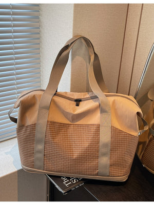 Spacious nylon travel duffel bag in tan with grid pattern lower panel and tan straps.