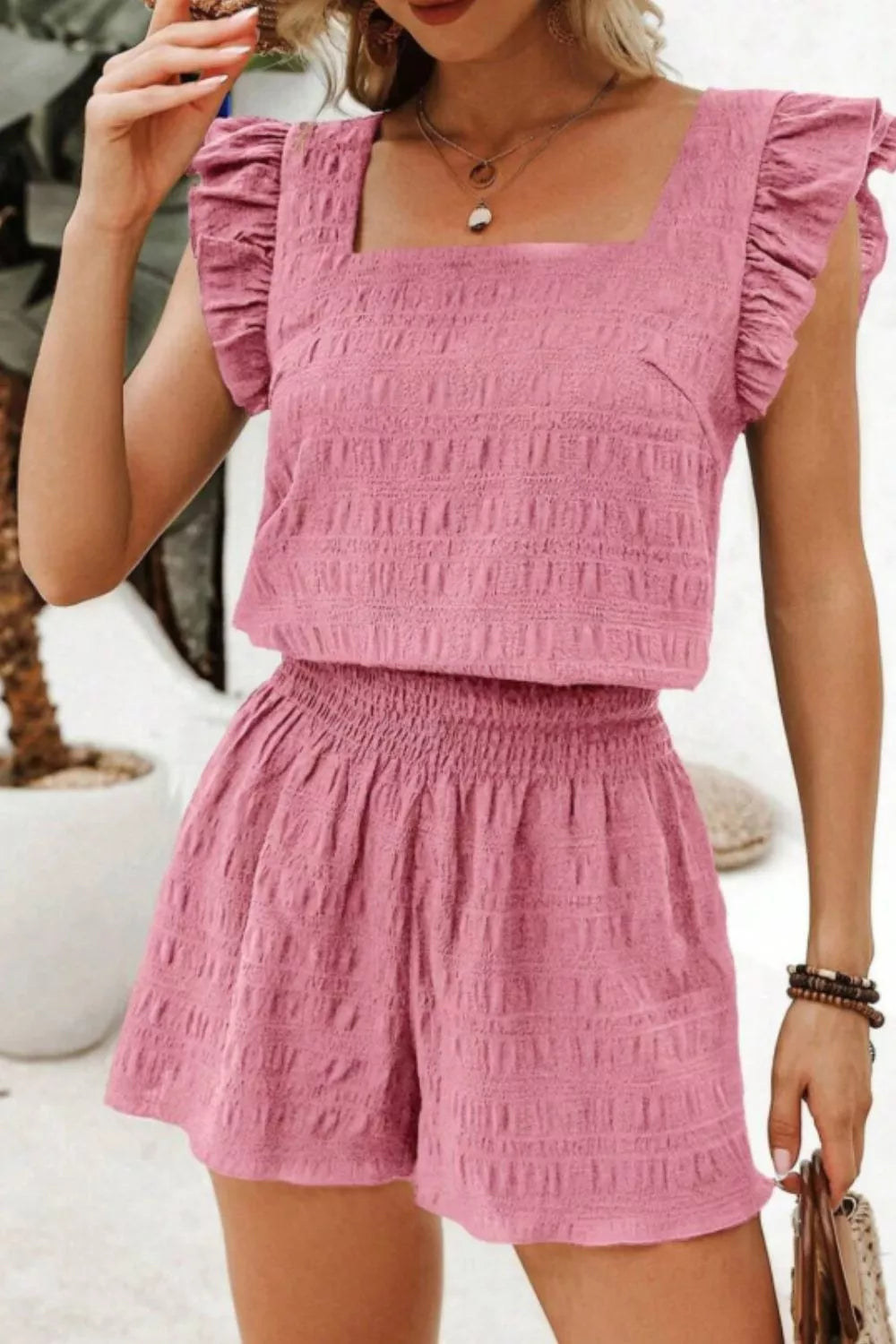 Pink textured two-piece set with ruffled sleeve crop top and smocked waist shorts
