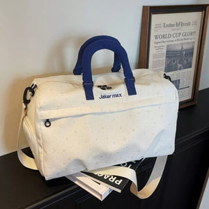 Cream white duffel bag with stars and moons pattern, blue handles, and adjustable strap.