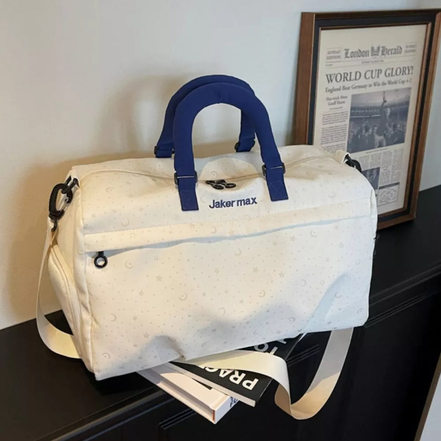 Cream white duffel bag with stars and moons pattern, blue handles, and adjustable strap.