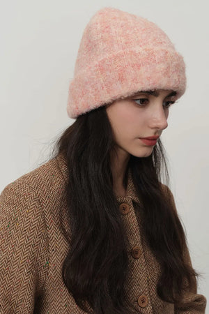 Textured bouclé knit beanie in pink, styled with a brown herringbone jacket.