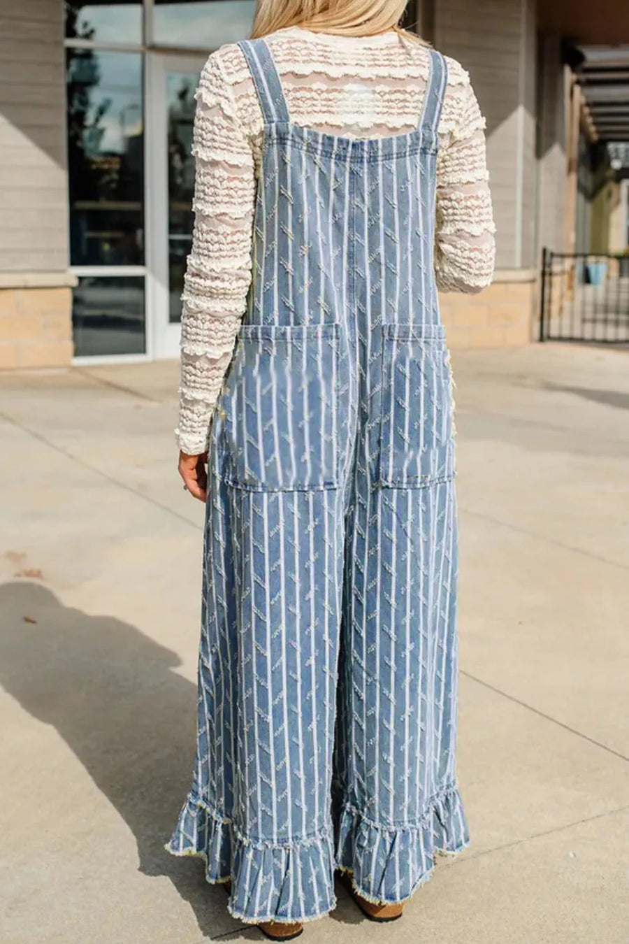 Striped distressed denim overalls with wide legs and ruffled hems.