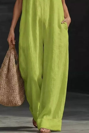 Lime halter neck jumpsuit with pockets and wide legs, worn with sandals and a straw bag.