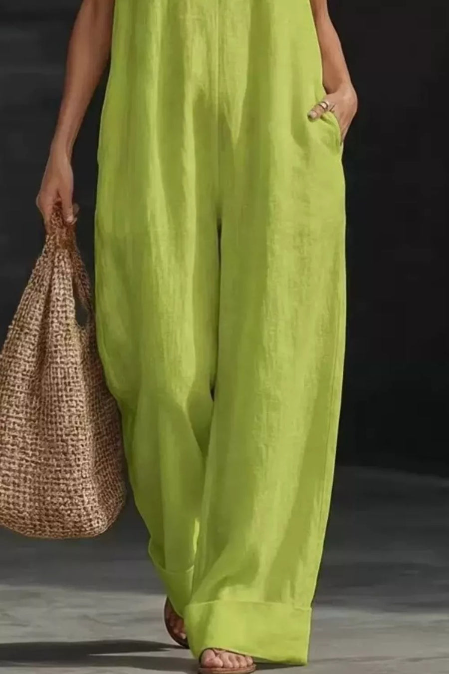 Lime halter neck jumpsuit with pockets and wide legs, worn with sandals and a straw bag.