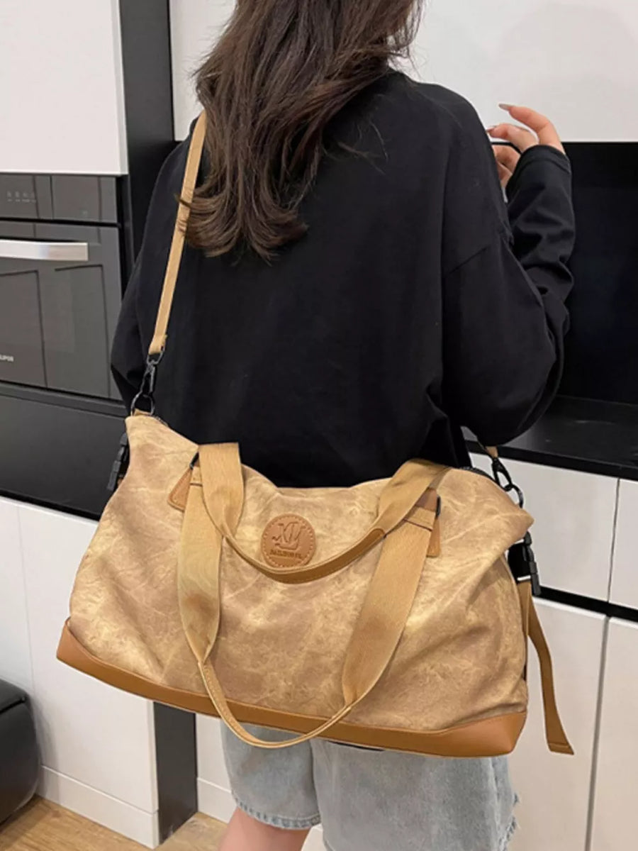 Brown Oxford cloth duffel bag with leather trim and detachable strap.