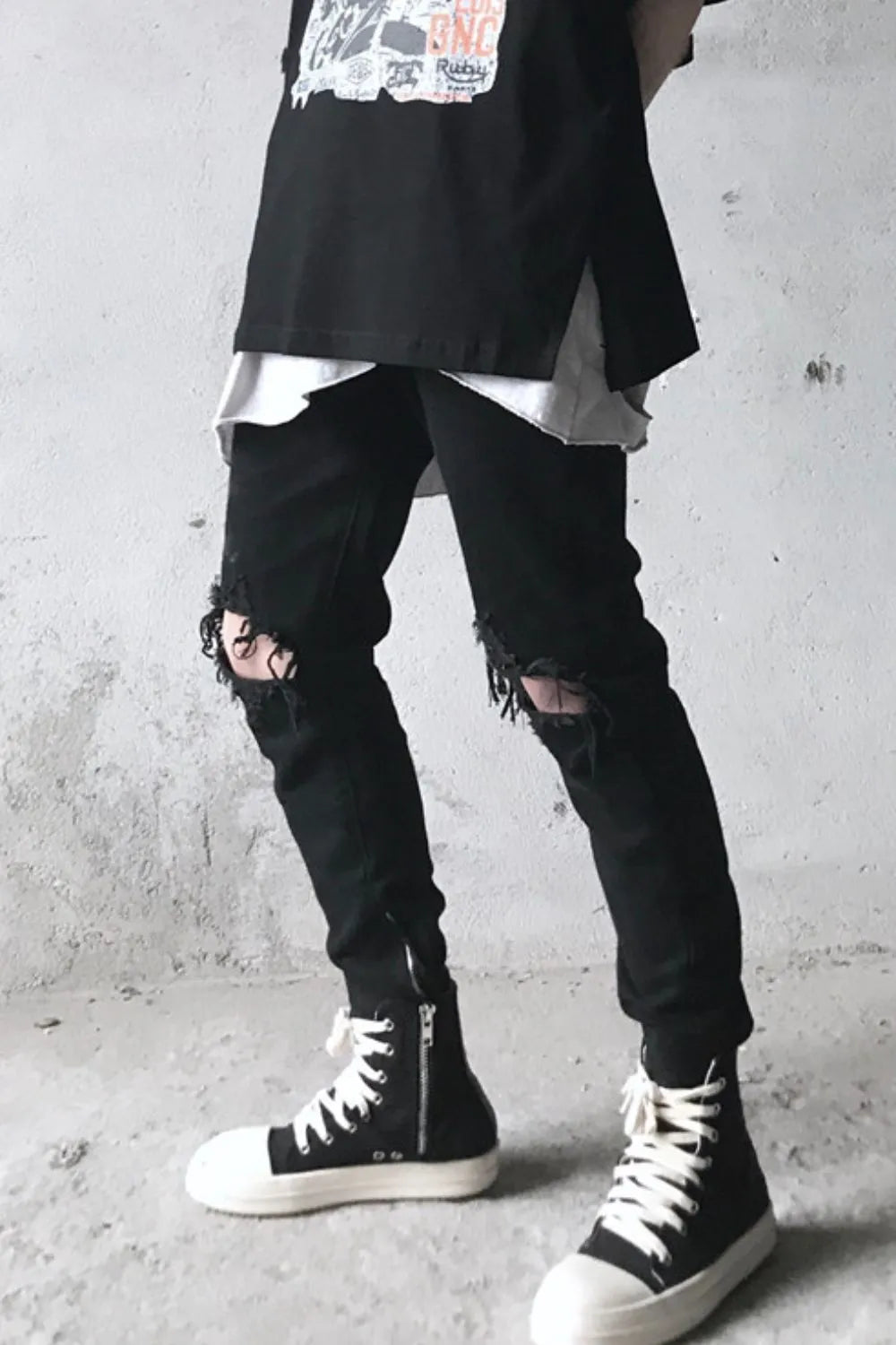 Black skinny fit denim jeans with distressed knees and ankle zippers.