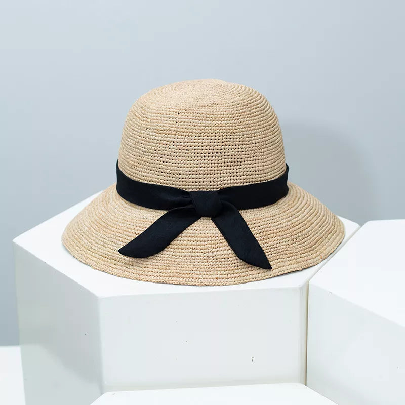 Chic wheat straw sun hat with black bow detail, adjustable.