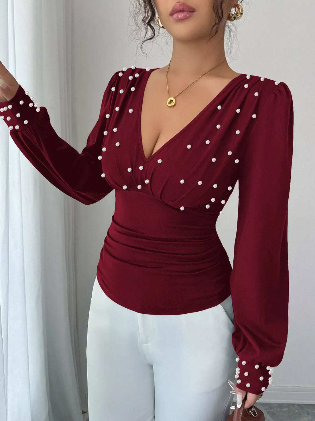 Burgundy ruched V-neck blouse with pearl embellishments and long sleeves