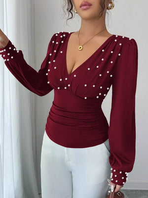 Burgundy ruched V-neck blouse with pearl embellishments and long sleeves