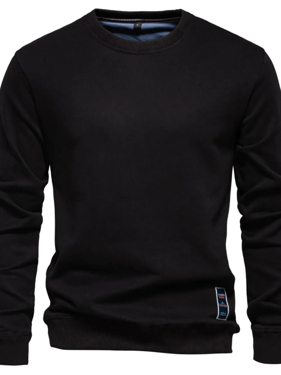 Black crewneck sweatshirt with subtle patch detail on hem