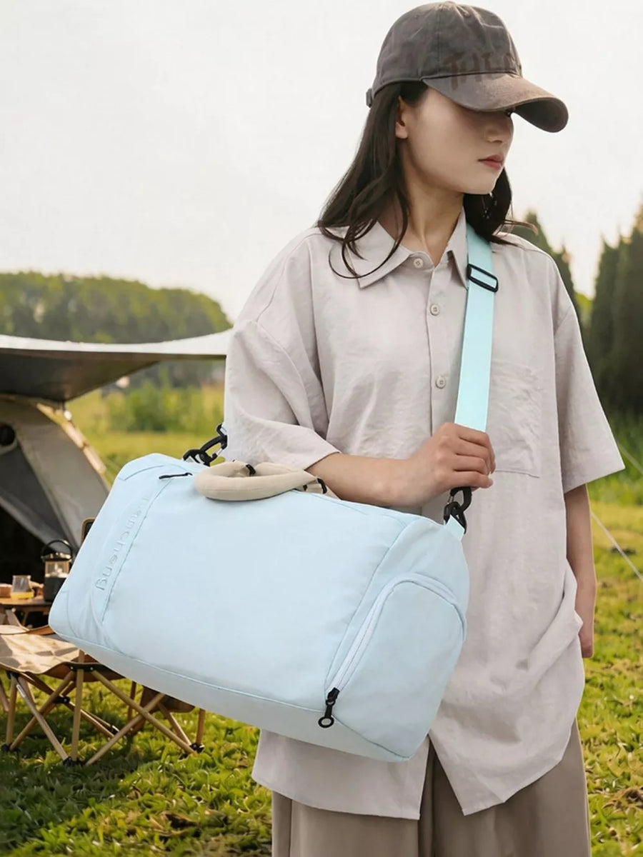 Light blue duffel bag with tan handle and light blue strap, side pocket.