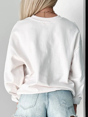 White crewneck sweatshirt with relaxed fit and cuffed sleeves, styled with denim shorts.