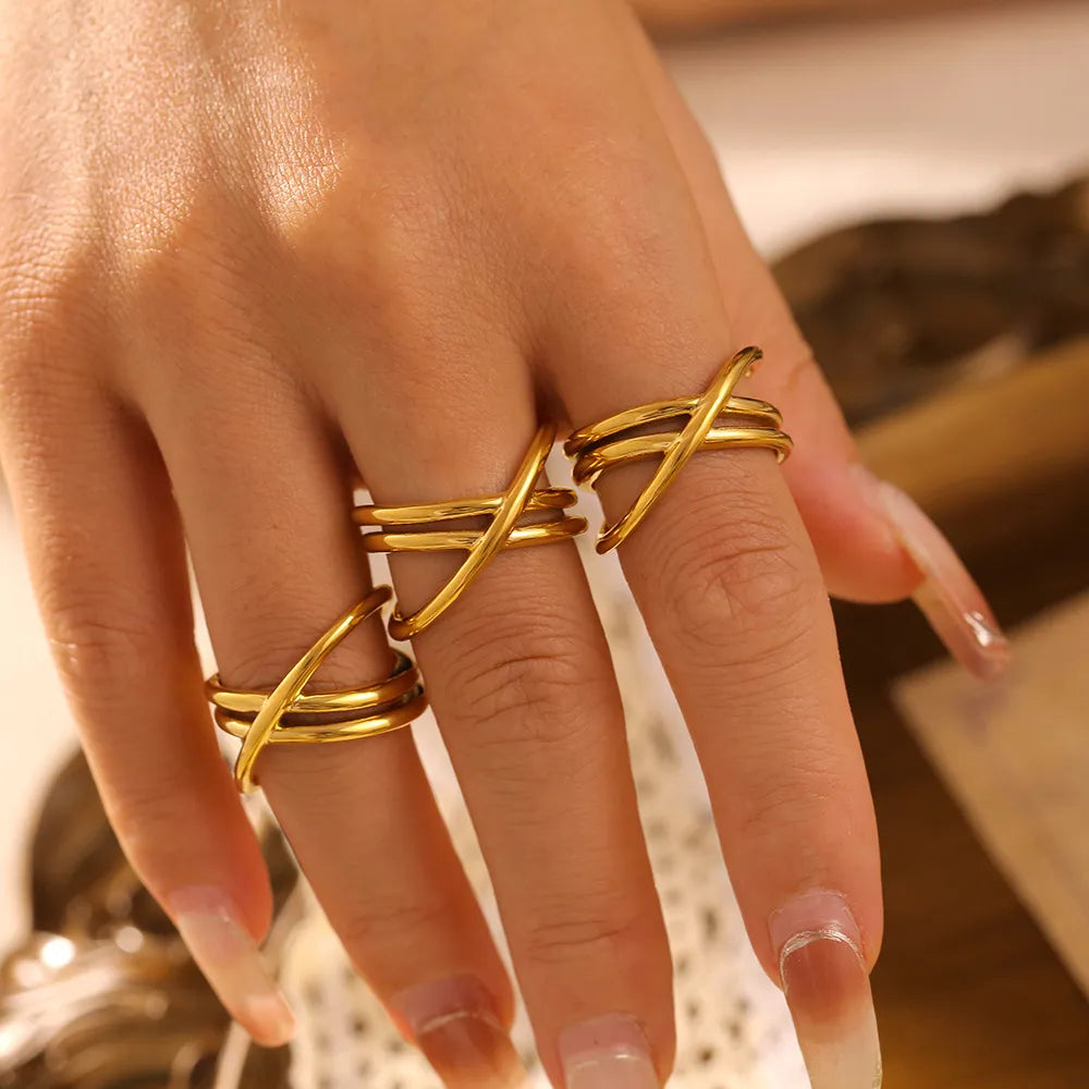 Gold intersecting band ring set with three stacked rings on fingers.