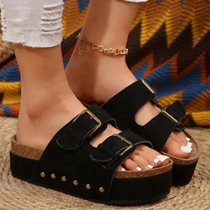 Black platform slides with double buckle straps and gold stud detail.