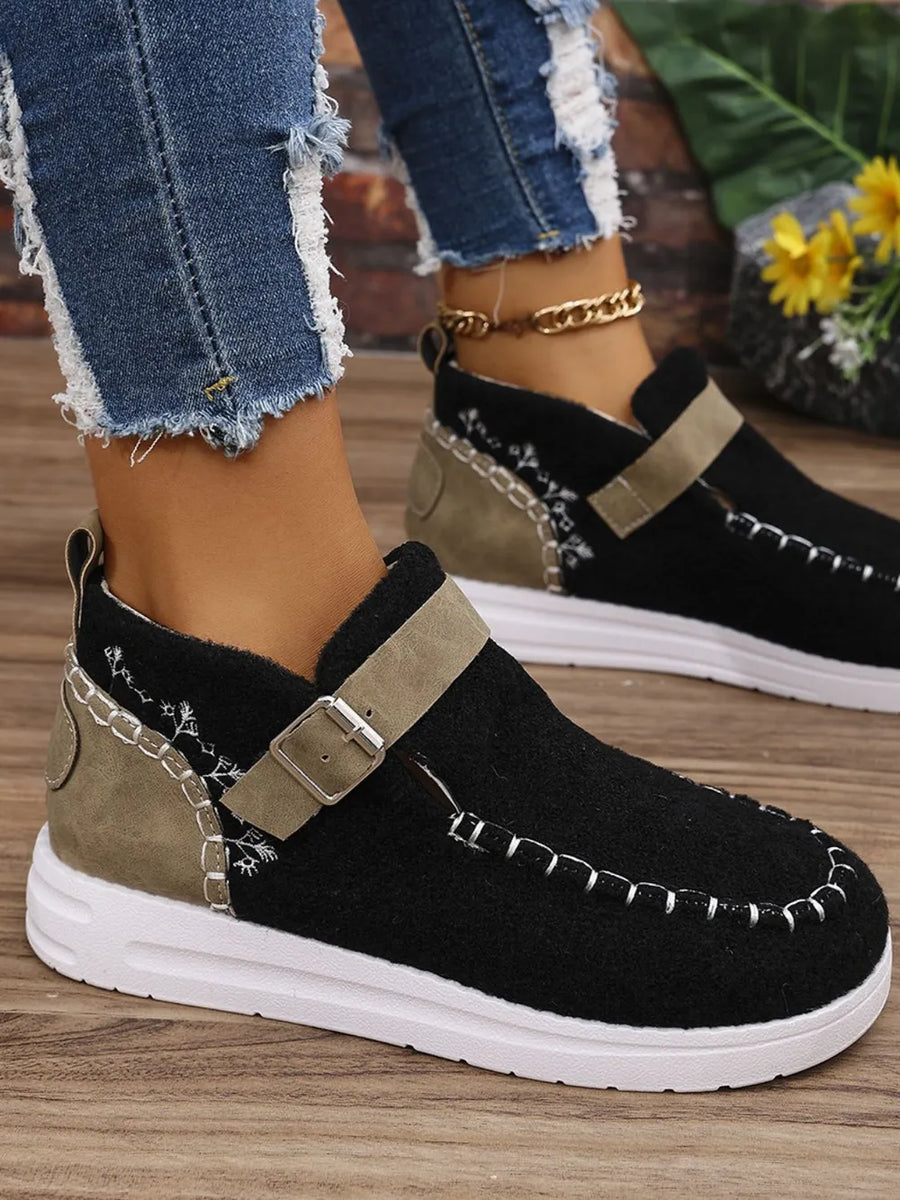Black textured stitch-detail buckle sneakers with tan strap and white sole.