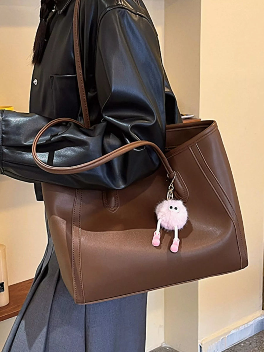 Brown PU leather tote bag with a fluffy pink charm and brown straps.