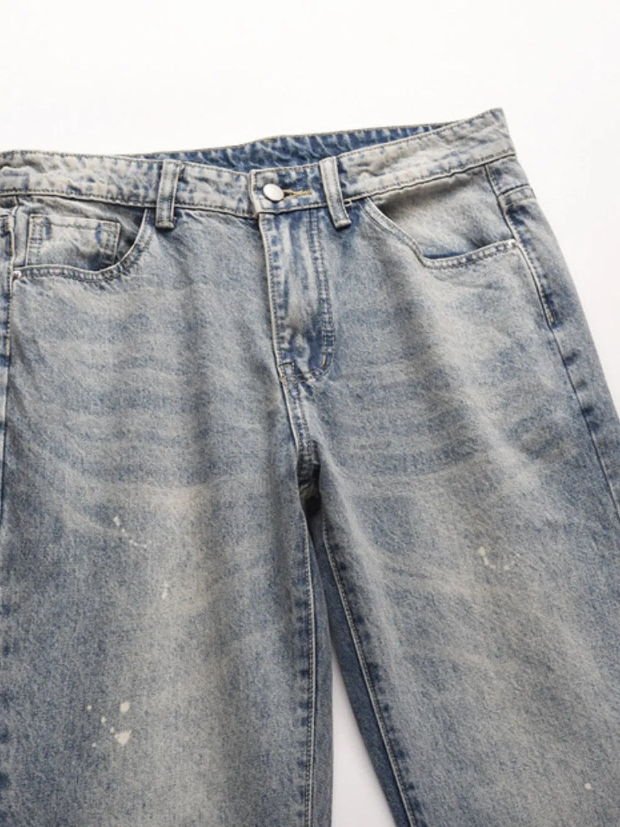 Distressed wash bootcut jeans in medium blue denim with raw hem detail.