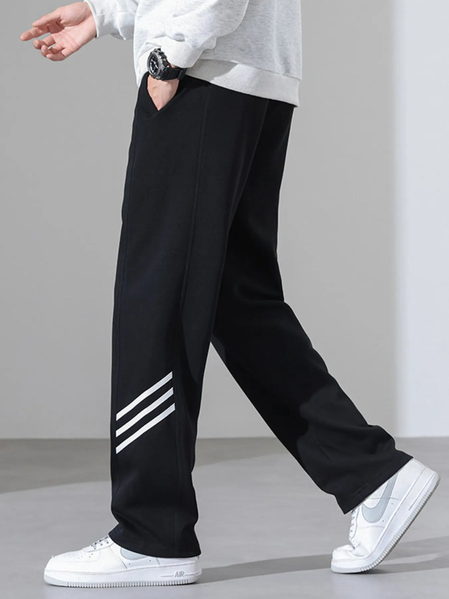 Black sweatpants with white stripes on the leg, loose fit, casual athleisure style.