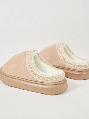 Tan shearling house slippers with embroidered trim and thick soles.