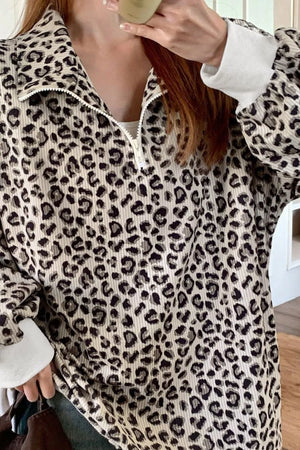 Leopard print quarter-zip sweatshirt with white cuffs and collar detail.