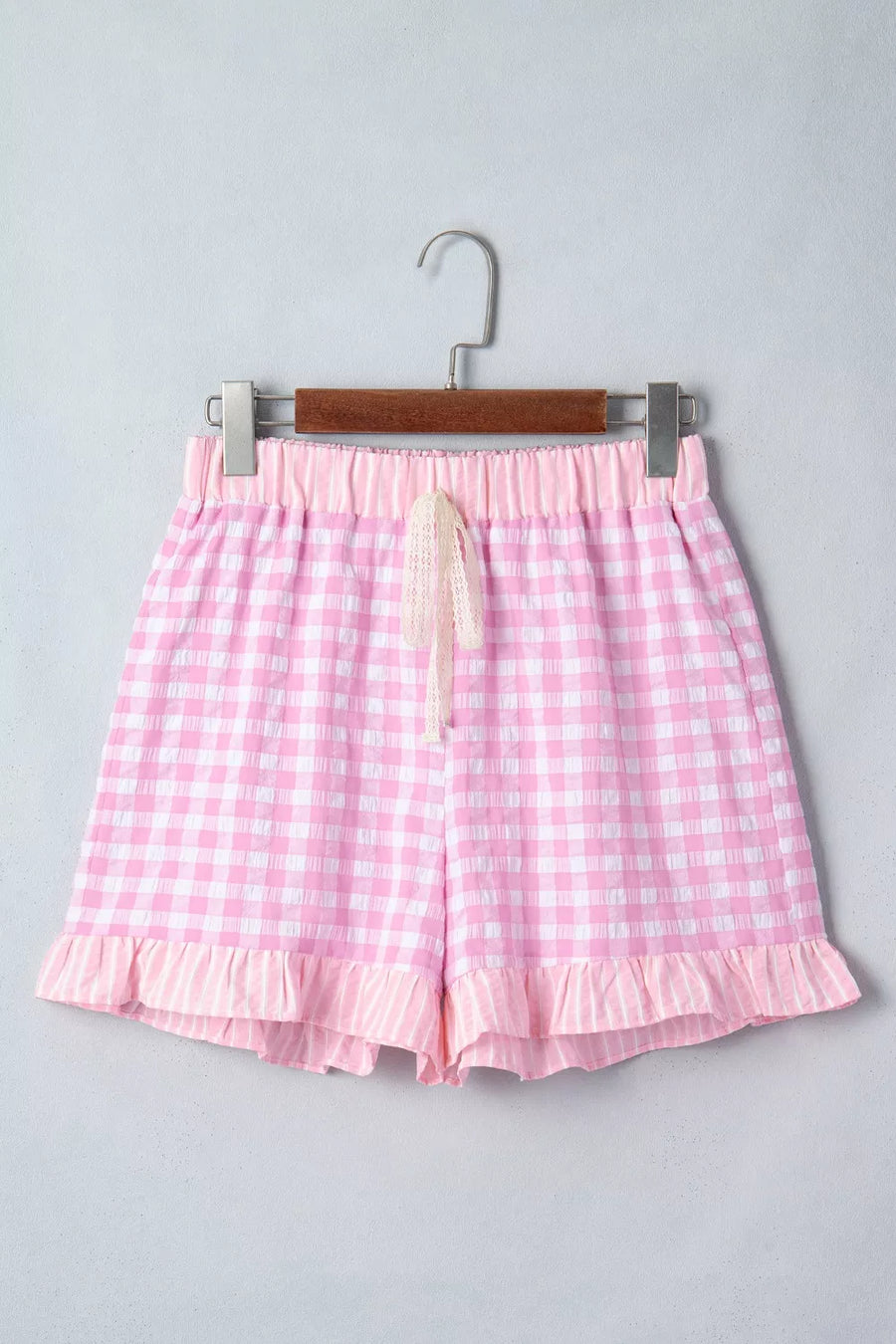 Pink gingham cotton shorts with drawstring and ruffle hem detail.