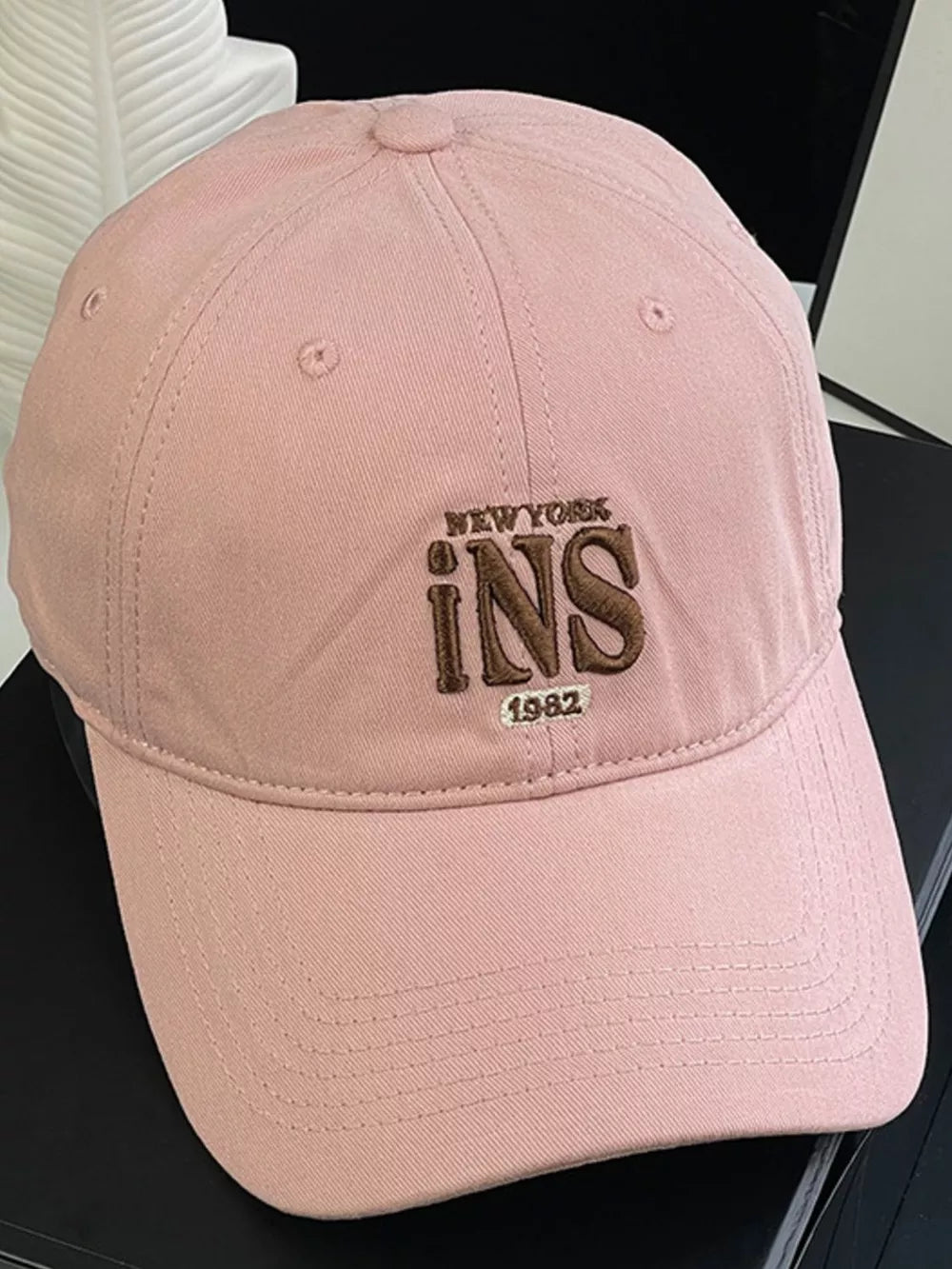 Pink baseball cap with embroidered New York INS 1982 detail