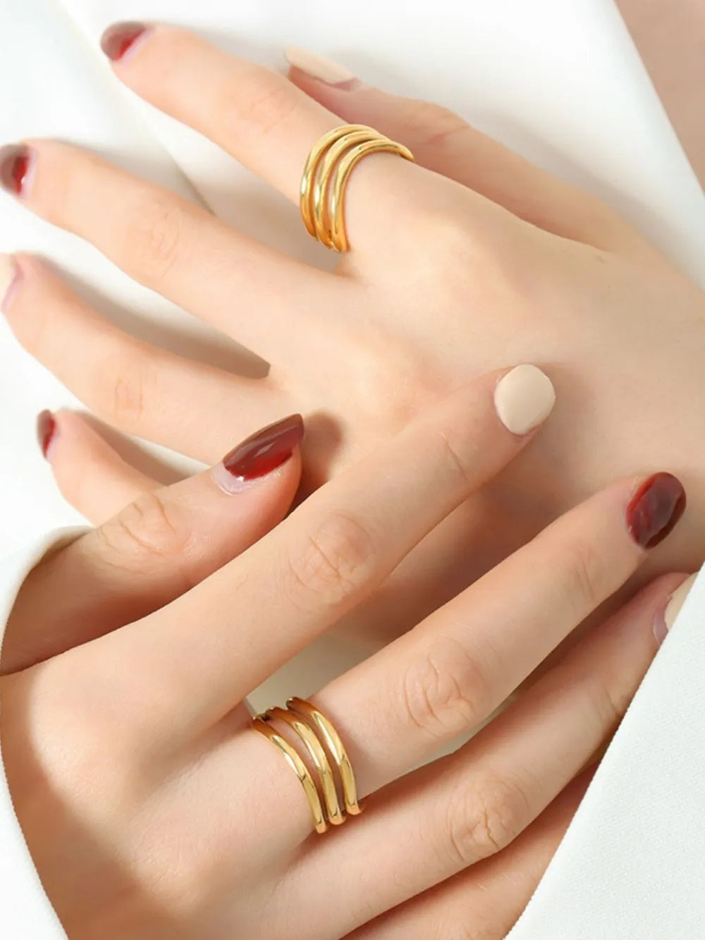 Gold triple-band sculptural ring with smooth, polished finish.