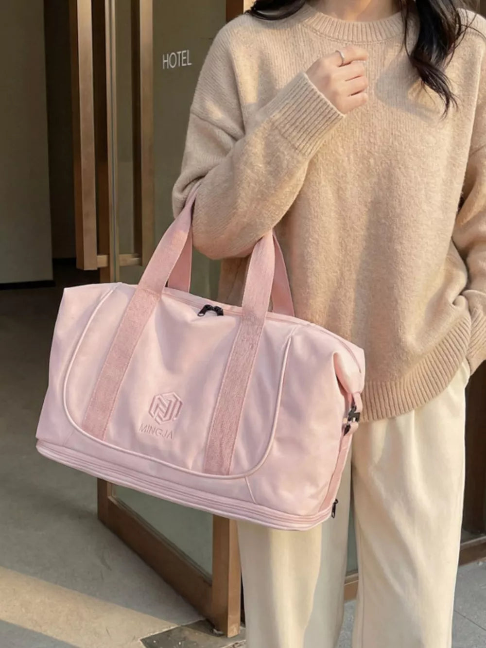 Pink duffel bag with embroidered logo and textured straps