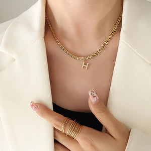 Gold chain necklace with a sparkling initial H pendant.