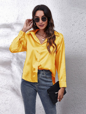 Gold silken button-down shirt with a relaxed fit and collar, styled with jeans.