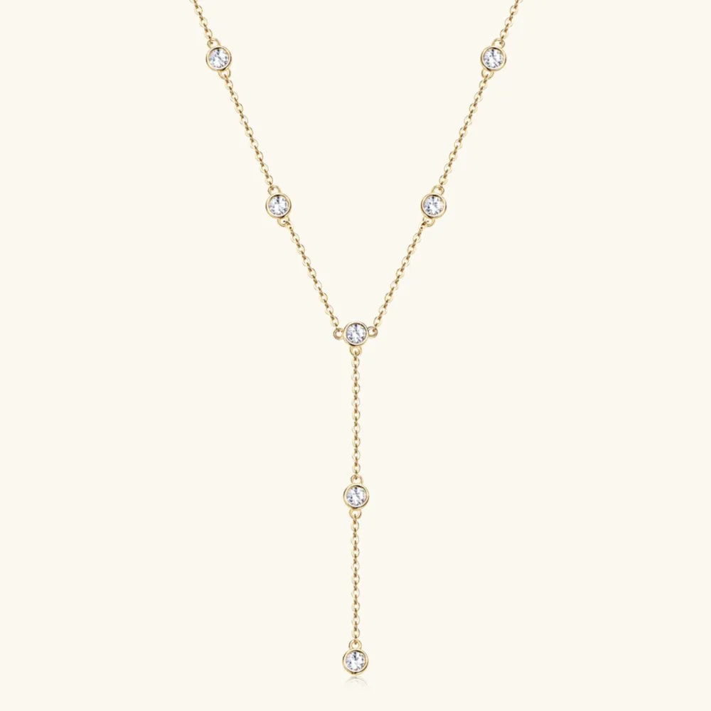 Gold lariat necklace with bezel-set moissanite drops.